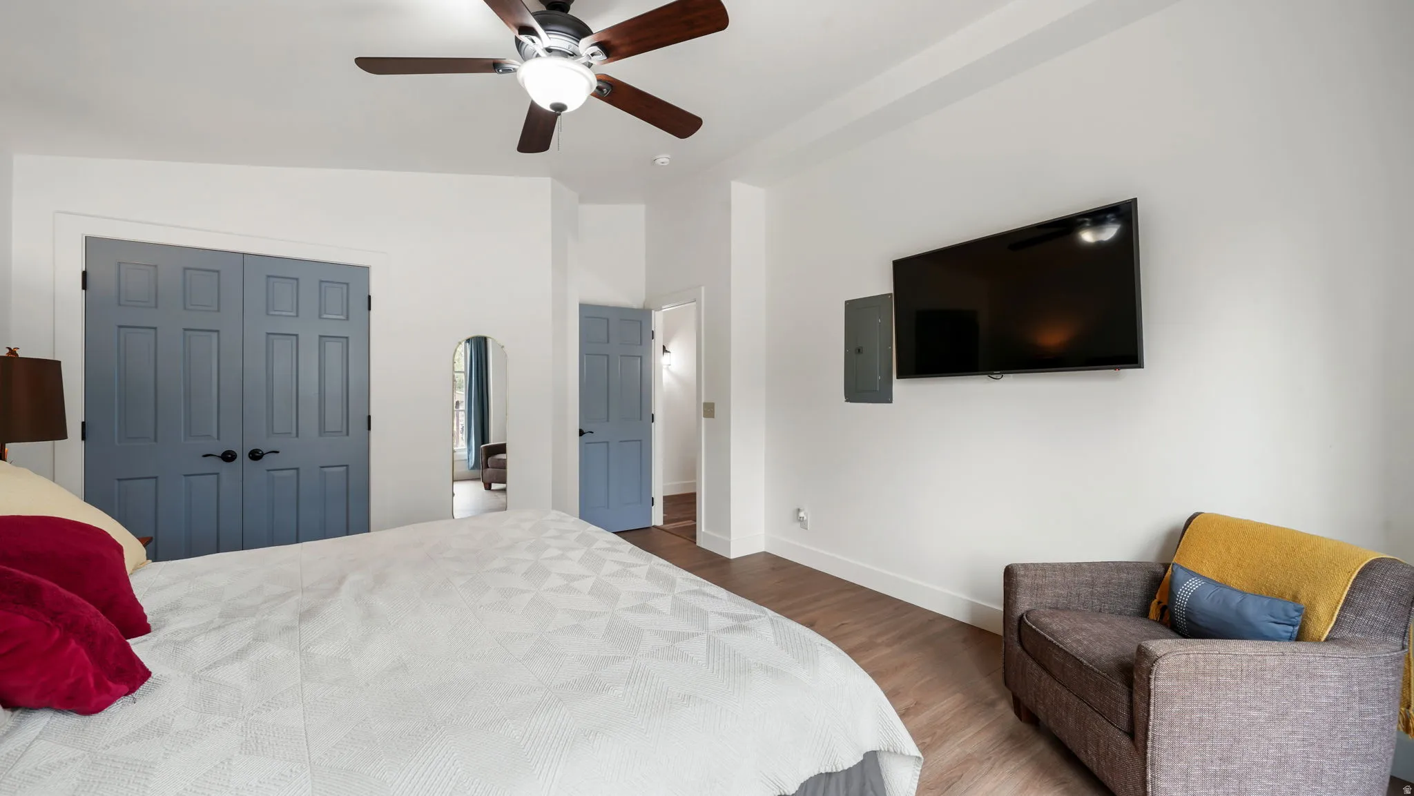 Interior space featuring wood-finish flooring, white walls, and a ceiling fan with integrated lighting