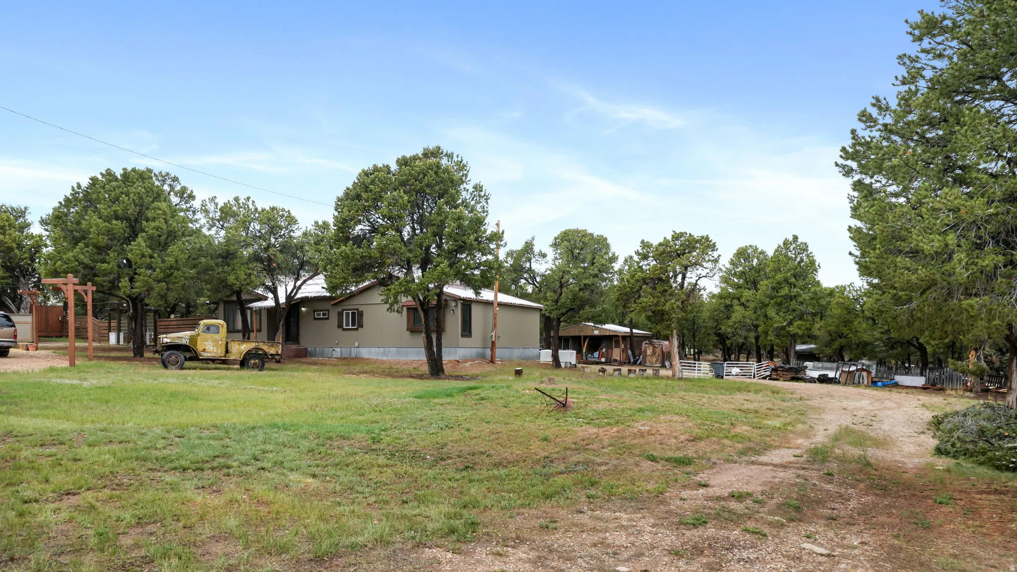 Expansive property featuring a single-story residence with a covered front porch, surrounded by mature trees