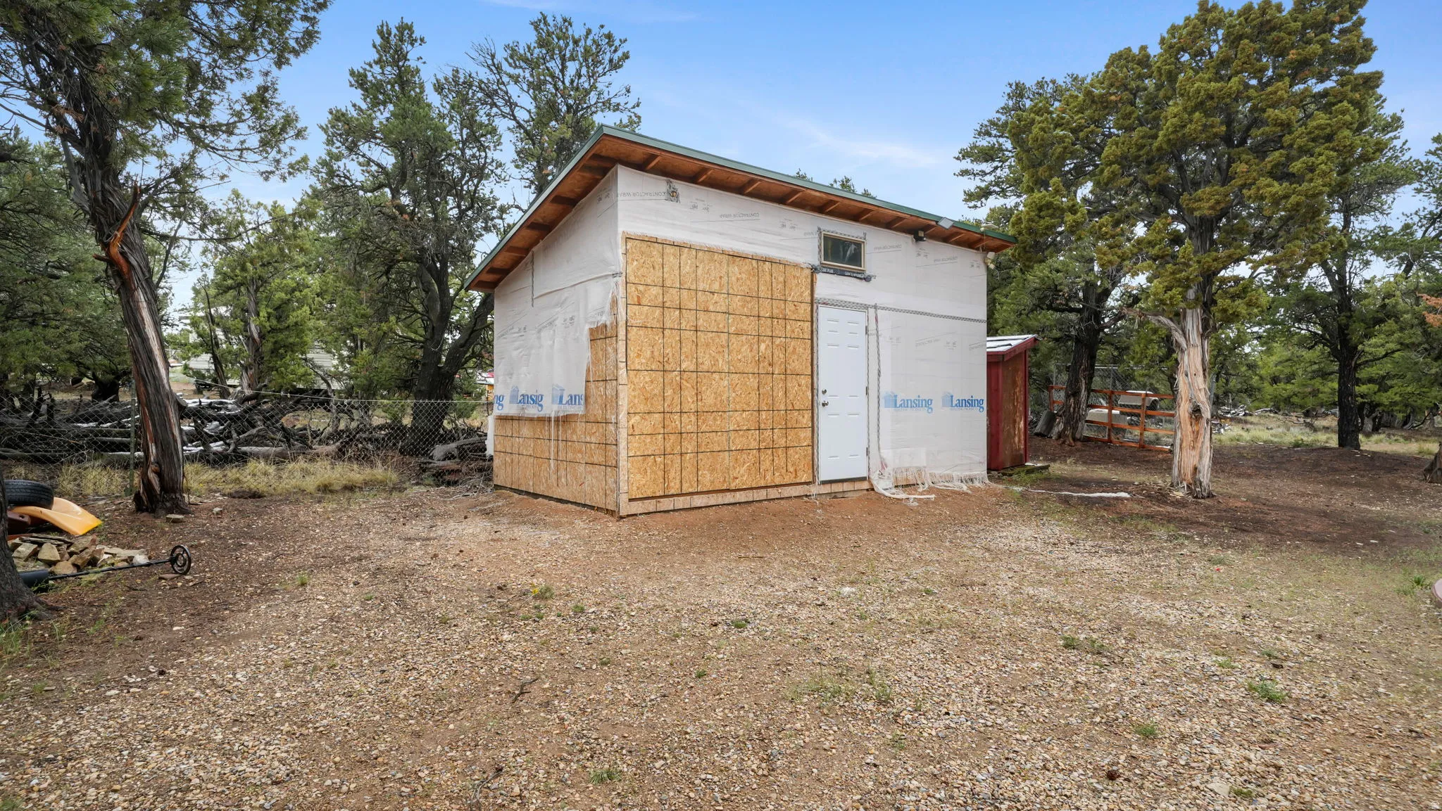 Detached utility structure with a pitched roof, partially finished exterior siding, and a single entry door