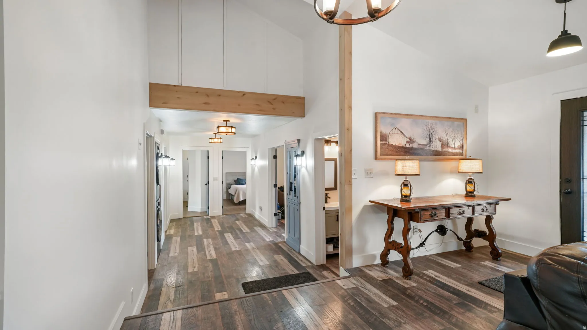 Spacious interior entryway featuring wood-finish flooring, vaulted ceilings, and exposed wood beams
