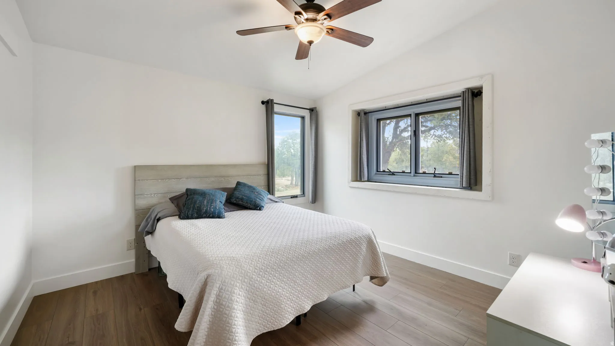 Spacious interior featuring wood-finish flooring, white walls, and an angled ceiling