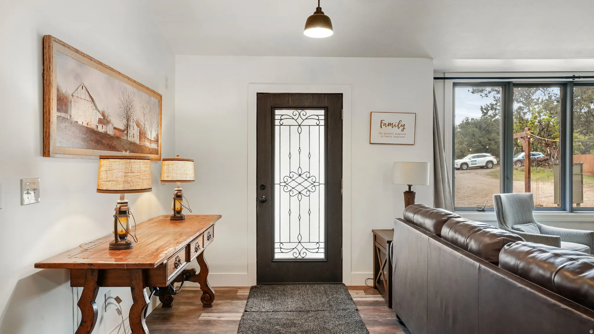 Entryway featuring a dark wood-finish door with decorative glass inserts, wood-finish flooring, and white walls