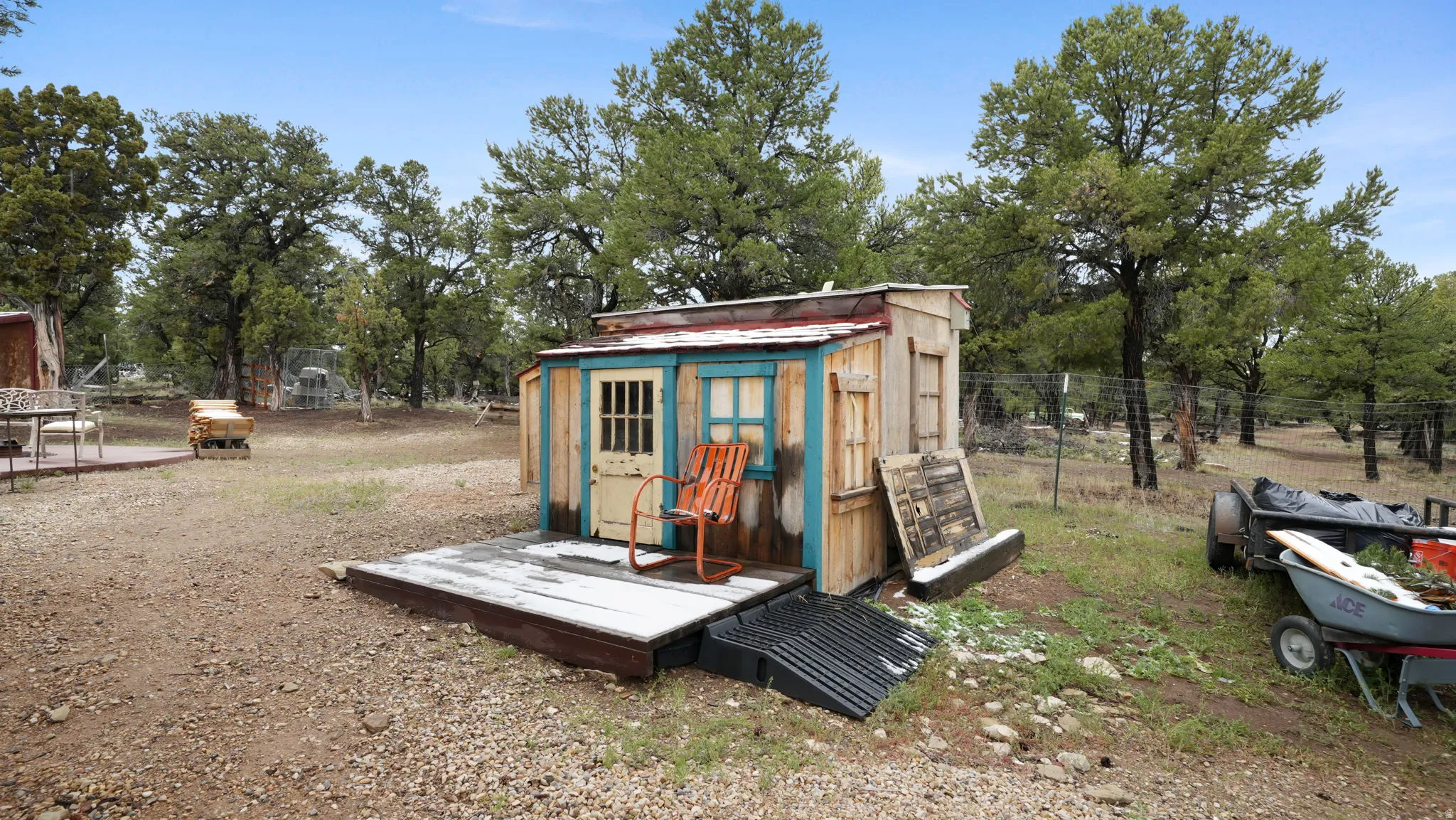 Rustic outbuilding with a raised wood deck and light blue trim detailing, featuring a wood panel door