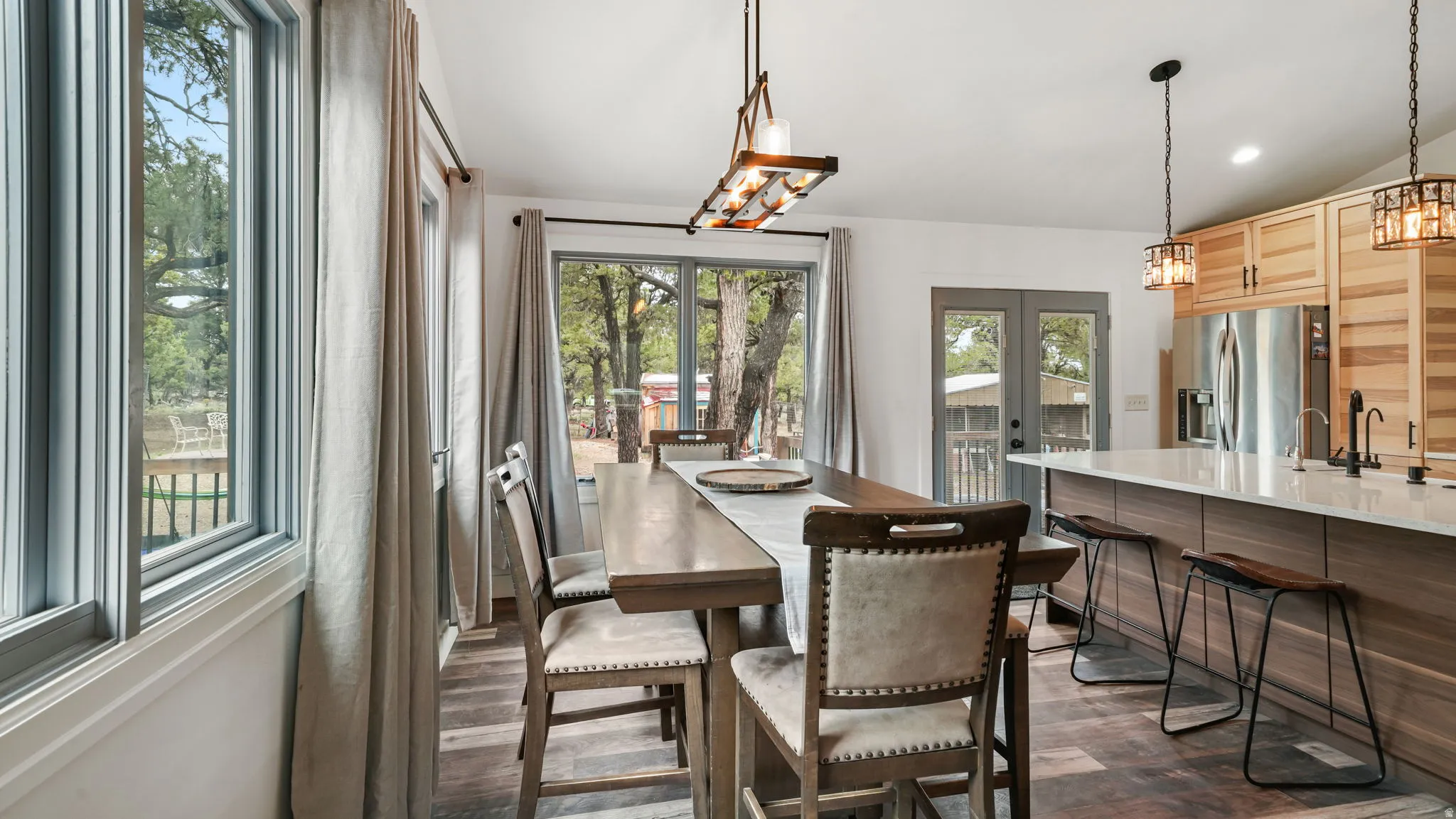 Open-concept dining area featuring wood-finish flooring, a contemporary linear chandelier, and a double-door entry to the exterior