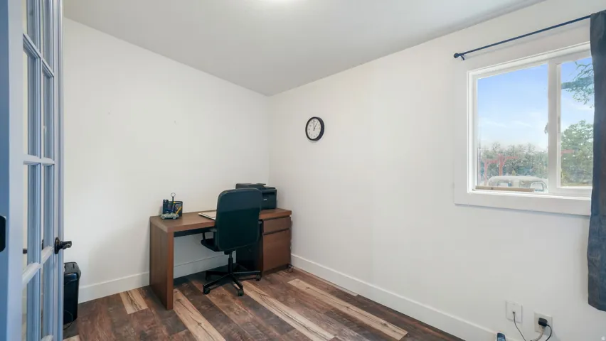Bright room featuring wood-finish flooring, white walls, and a large window