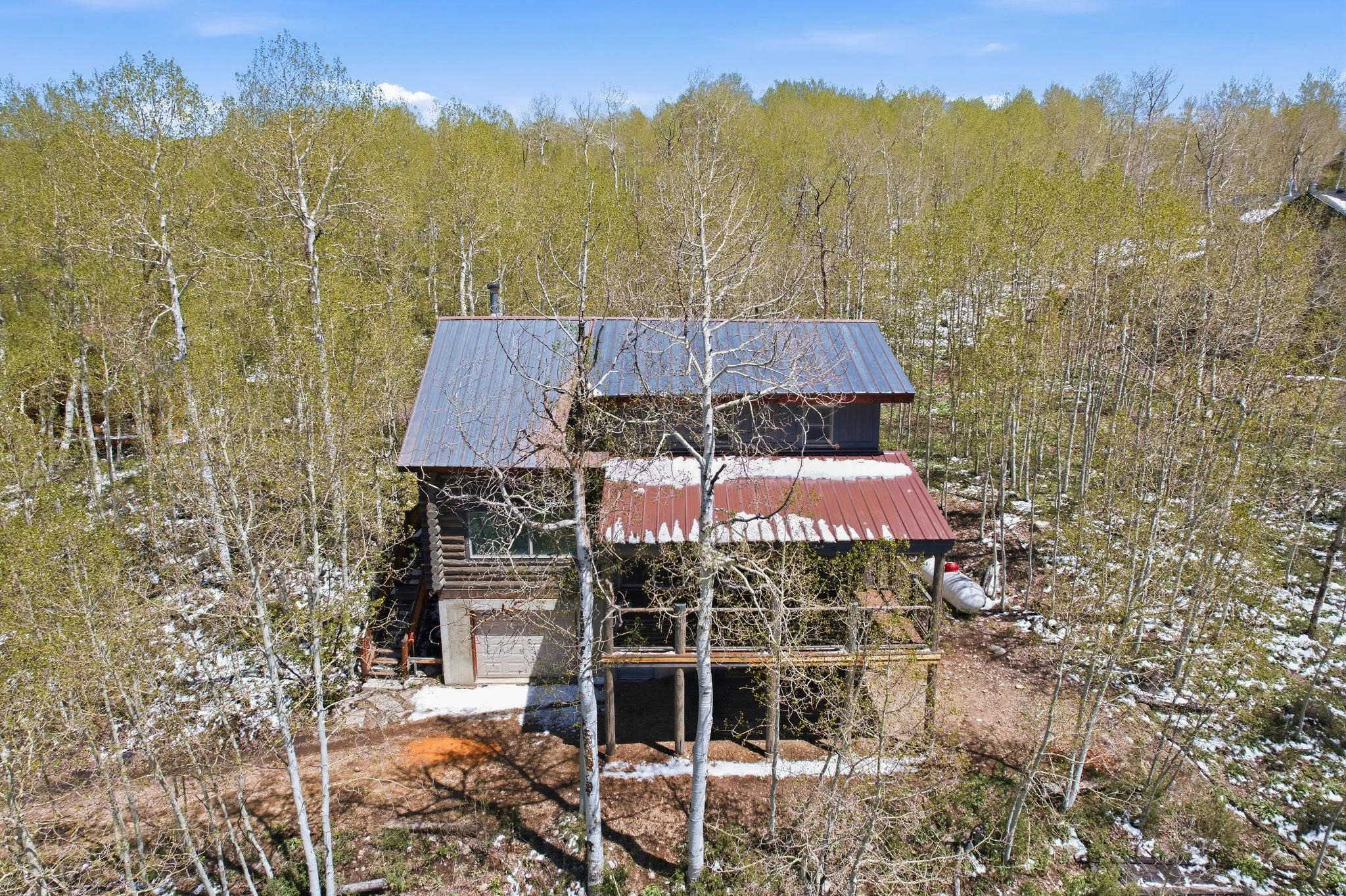 Rustic cabin exterior with a combination of wood siding and stone foundation, featuring a two-story design