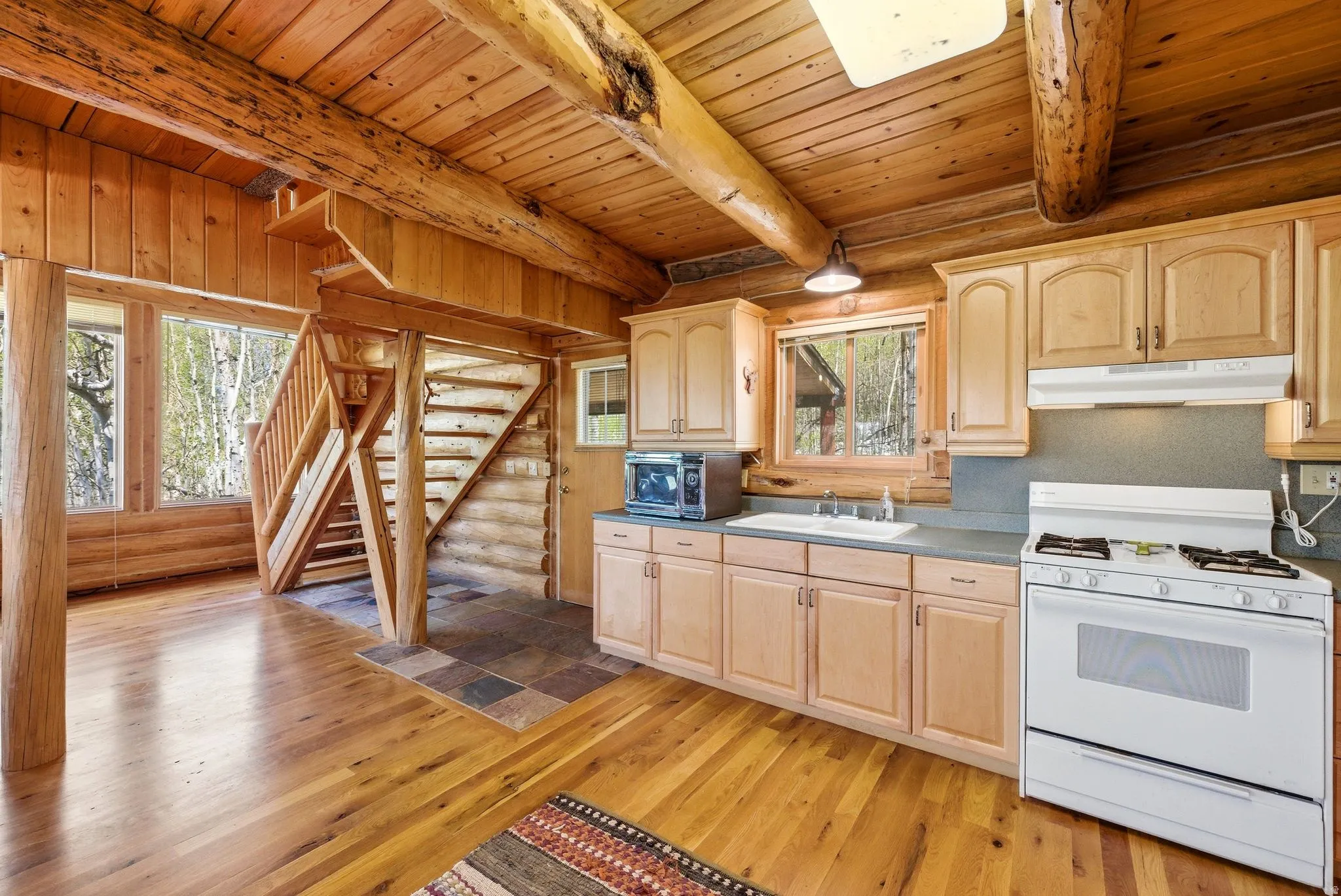 Log cabin interior featuring exposed wood beams, wood-finish flooring, and natural wood paneling
