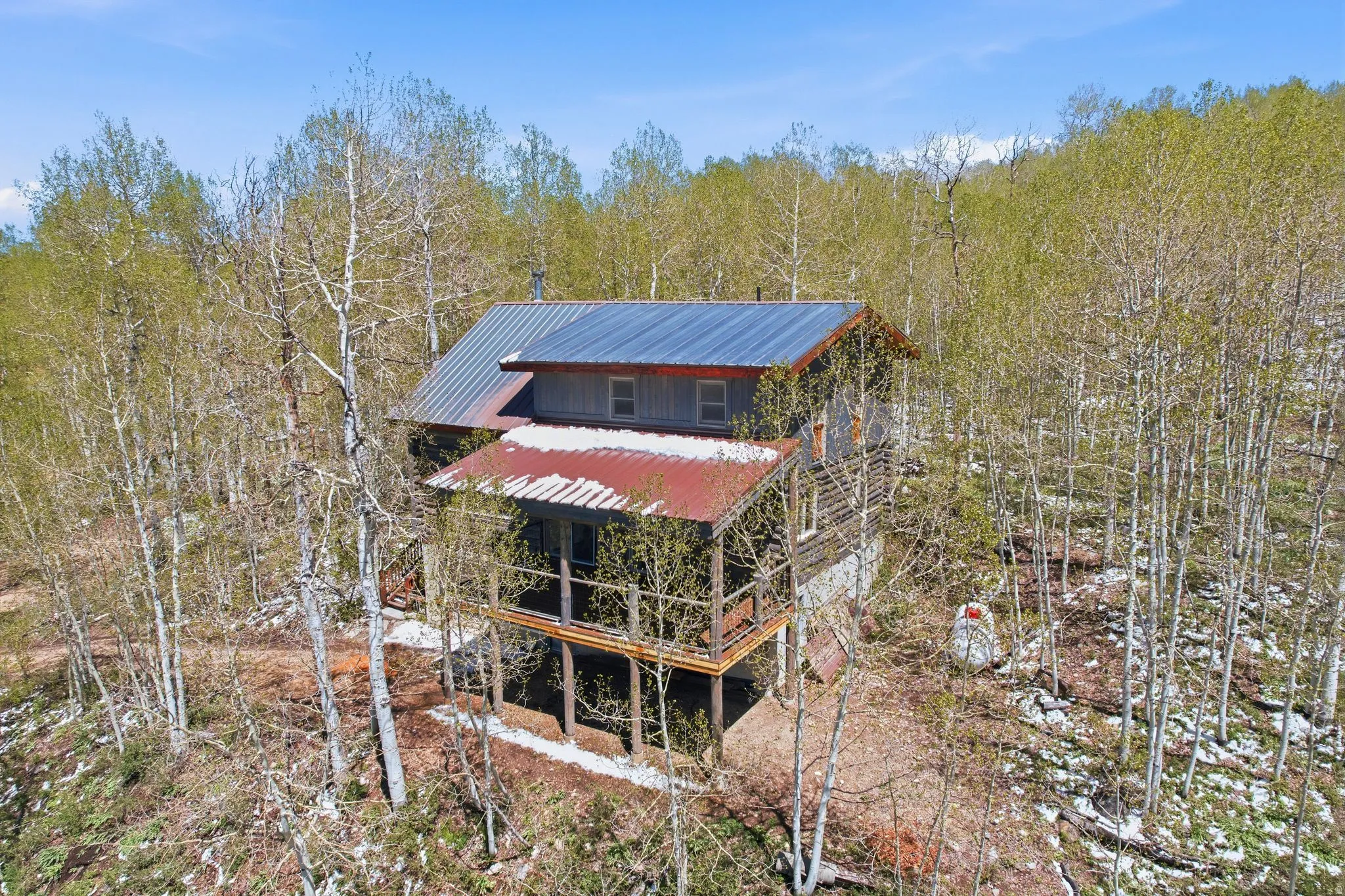 Rustic cabin featuring a metal roof, log siding, and an elevated porch
