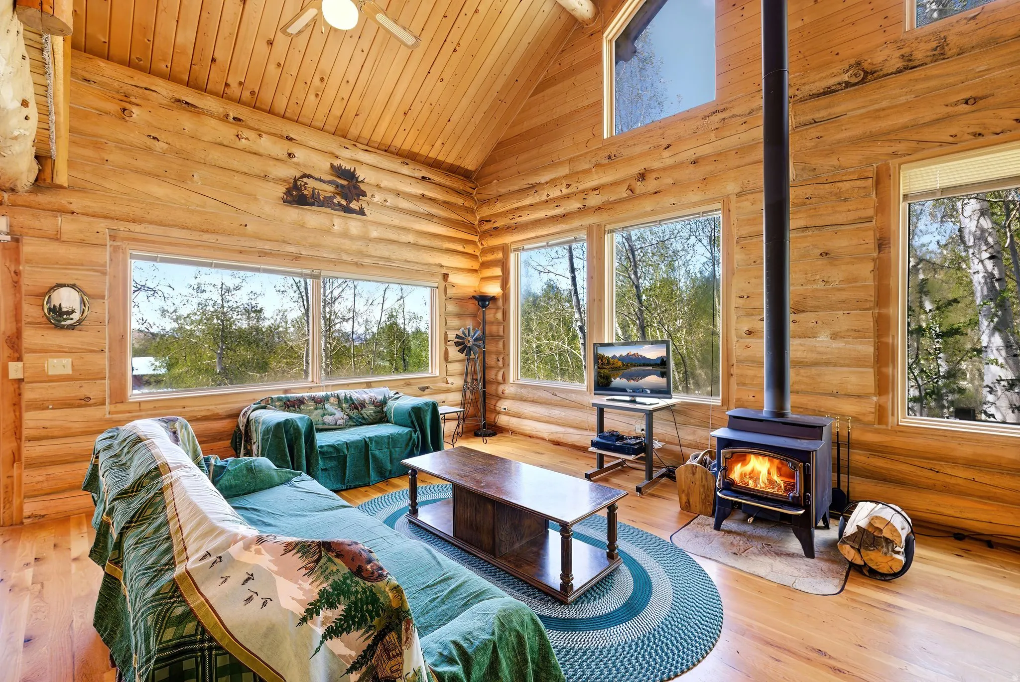 Spacious living area featuring log walls, vaulted wood plank ceilings, and wood-finish flooring