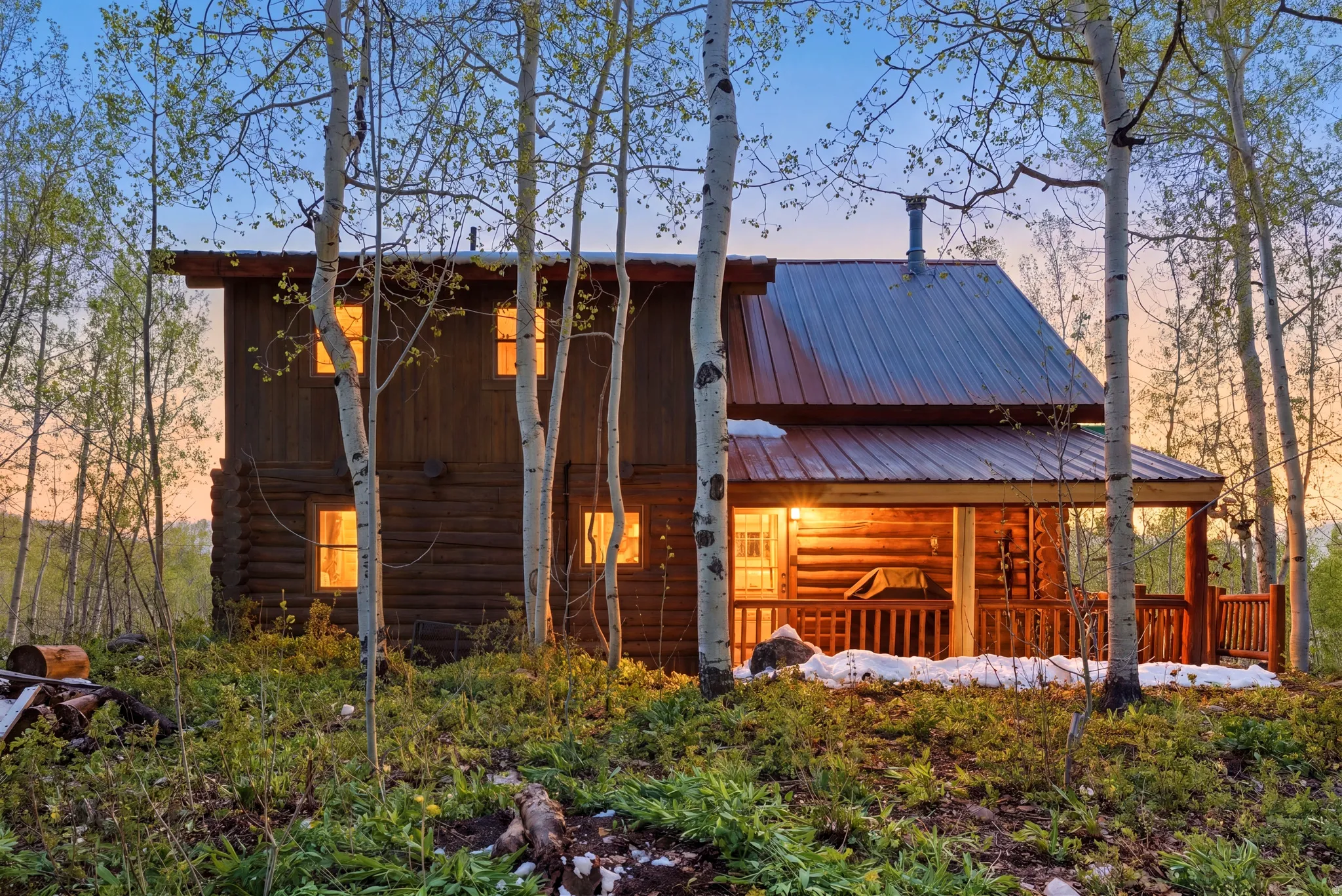 Rustic log cabin exterior with a metal roof and an inviting covered porch