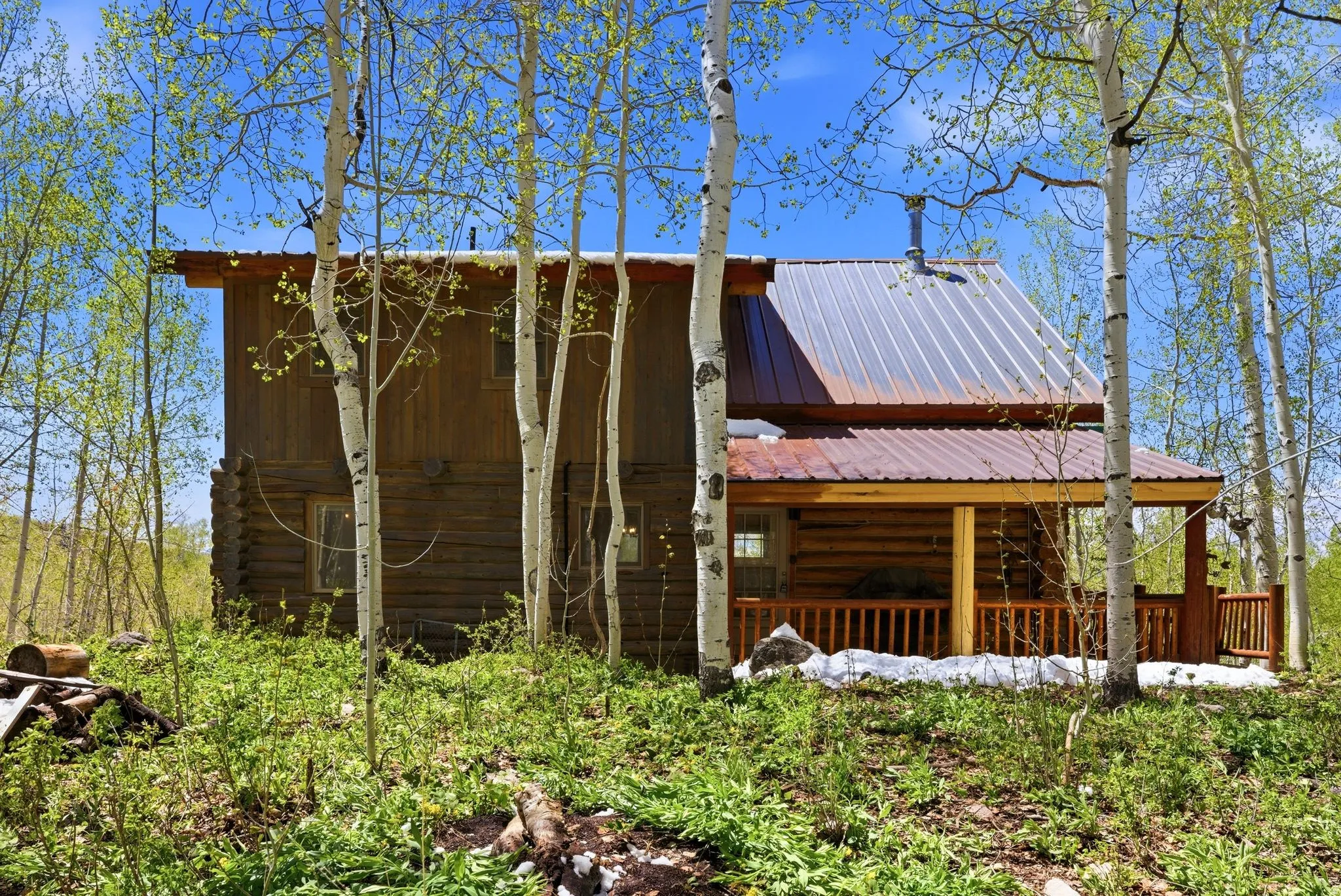 Log cabin exterior featuring a covered porch, wood siding, and a metal roof