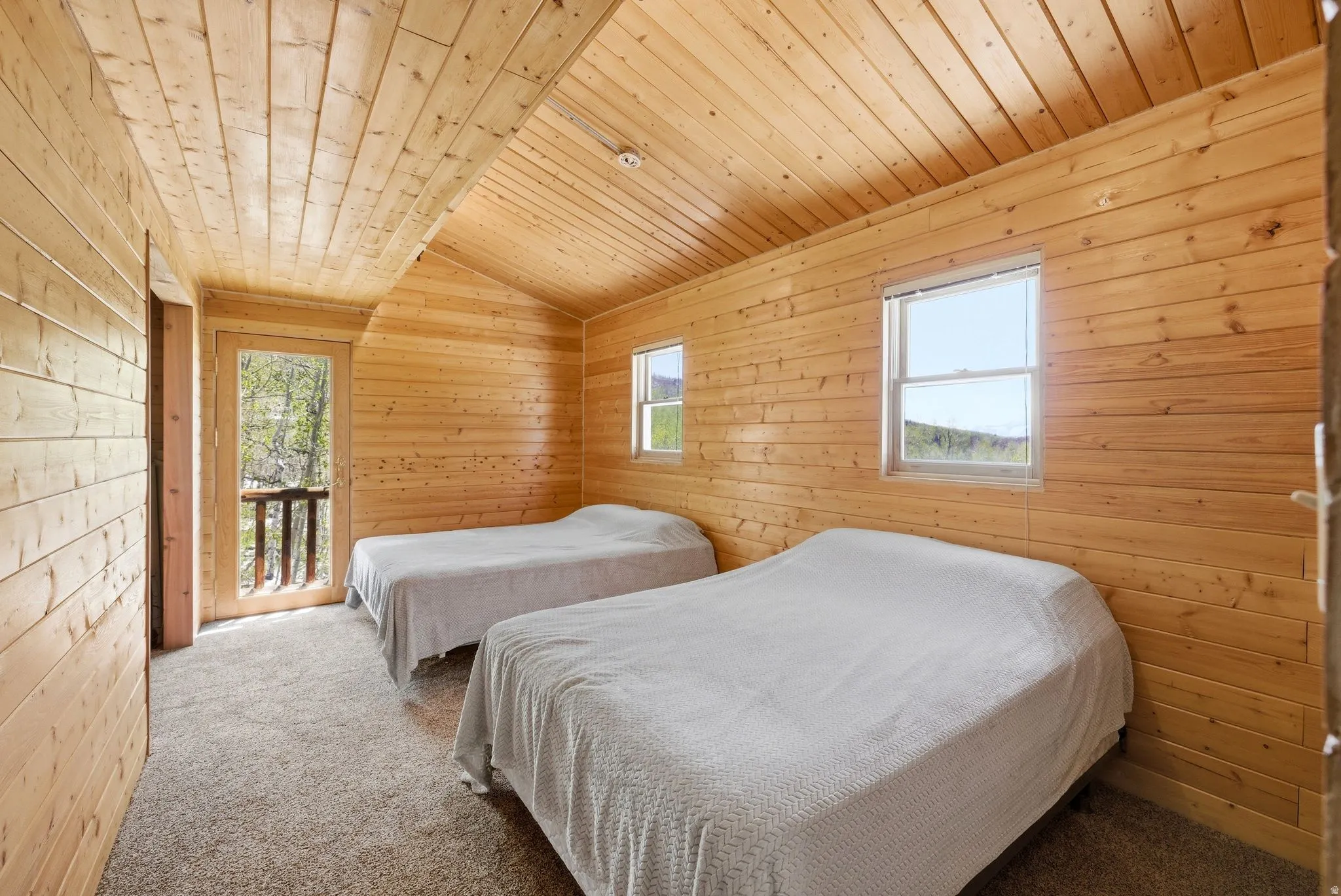 Wood-paneled interior featuring a vaulted ceiling and textured carpet flooring
