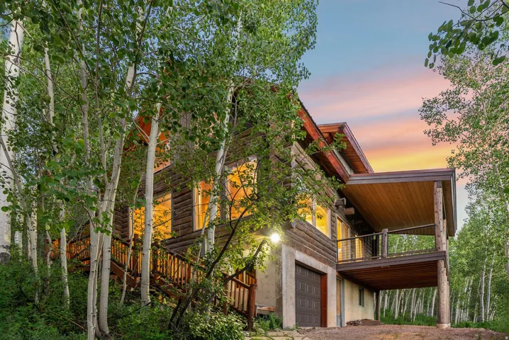 Wood-sided exterior featuring a covered deck with wood planking and metal railings