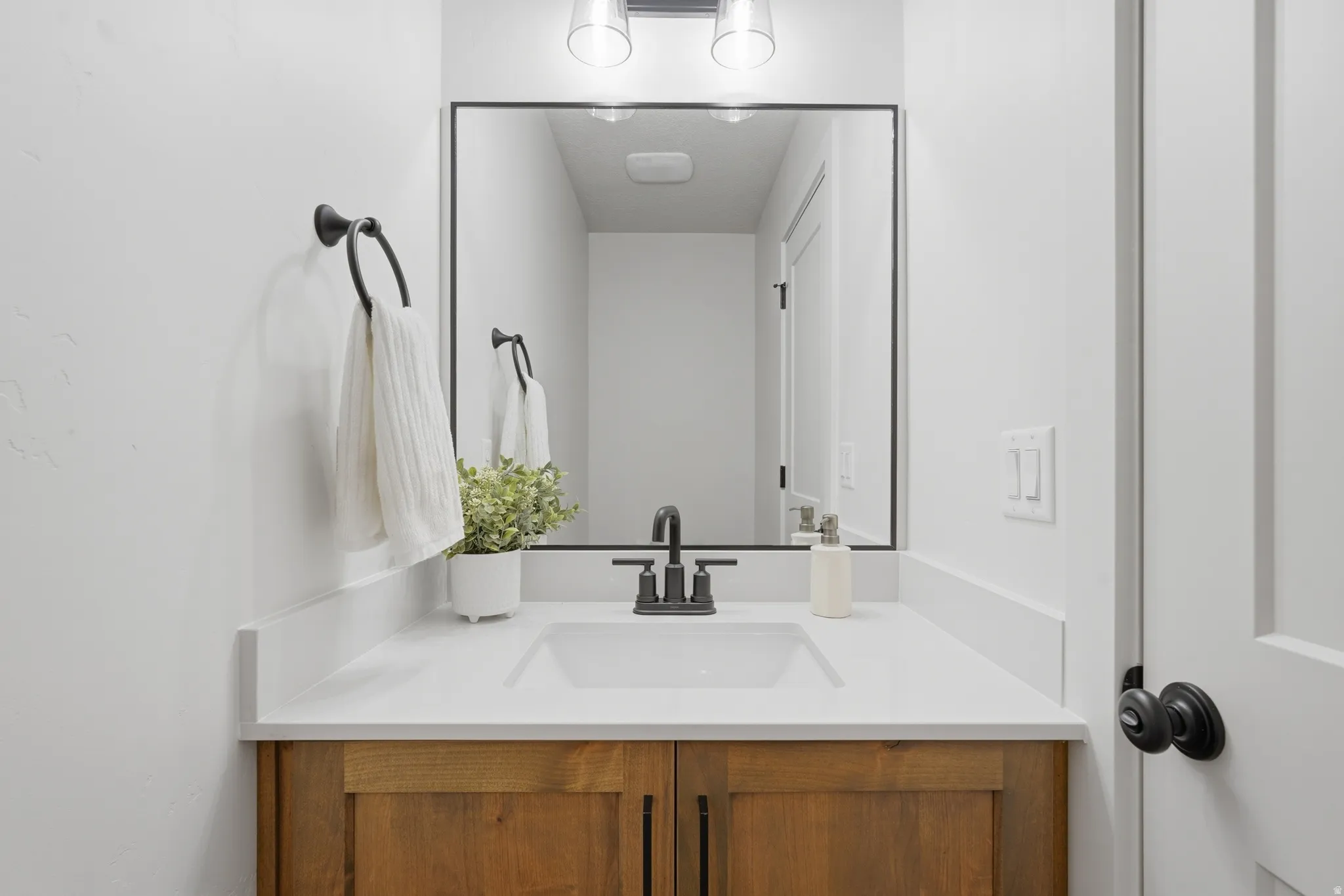 Bathroom vanity featuring a white rectangular sink, matte black faucet, and a large mirror with a black frame