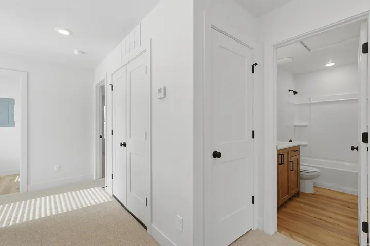 Hallway featuring recessed lighting, white doors with matte black hardware, and neutral carpet