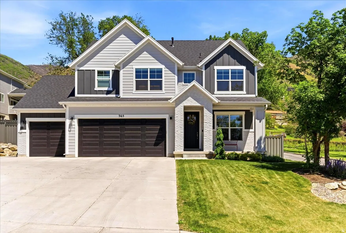 Modern two-story home featuring a combination of light gray siding, dark gray vertical board and batten accents, and white brickwork