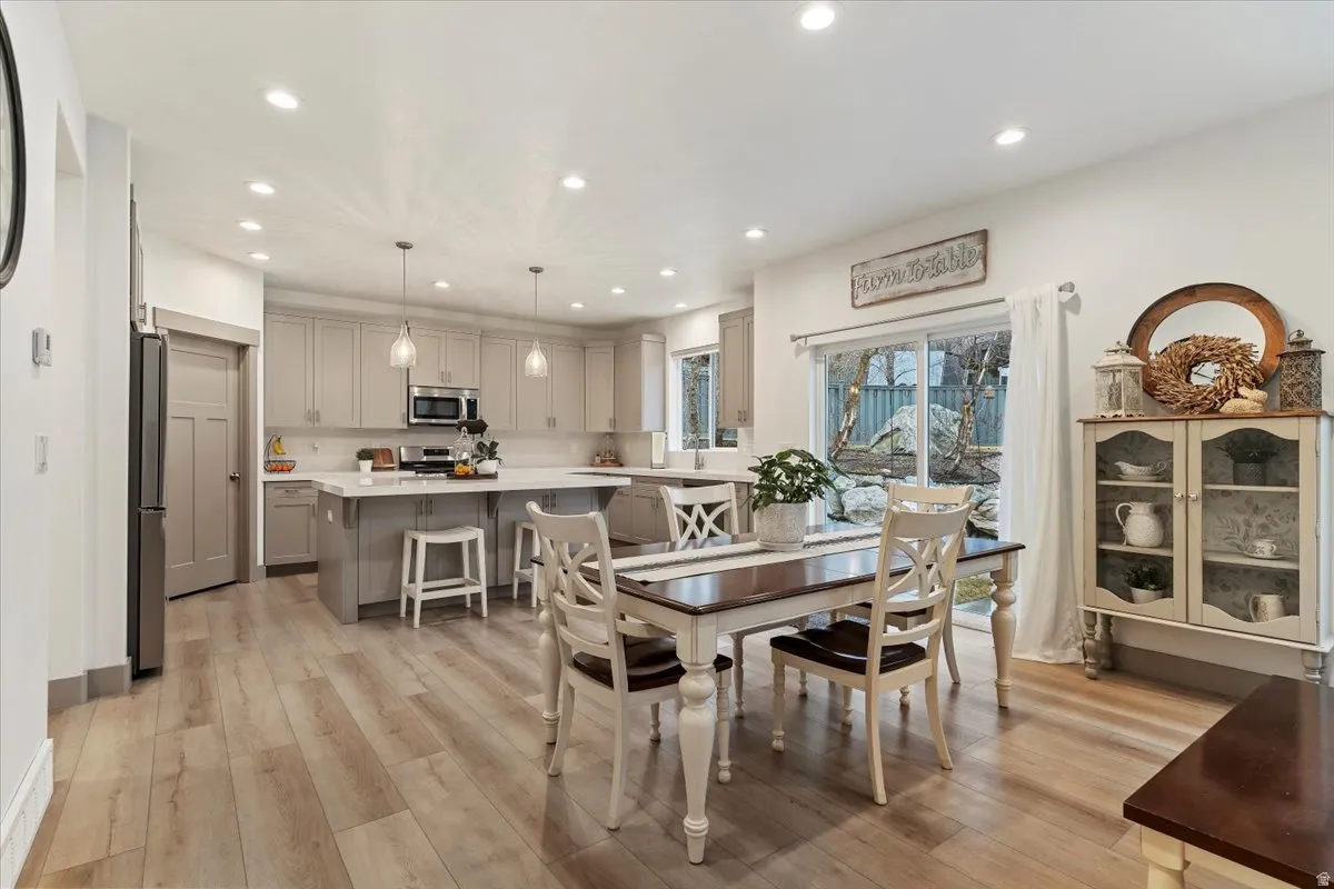 Spacious kitchen and dining area with light wood-finish flooring, recessed lighting, and a sliding glass door