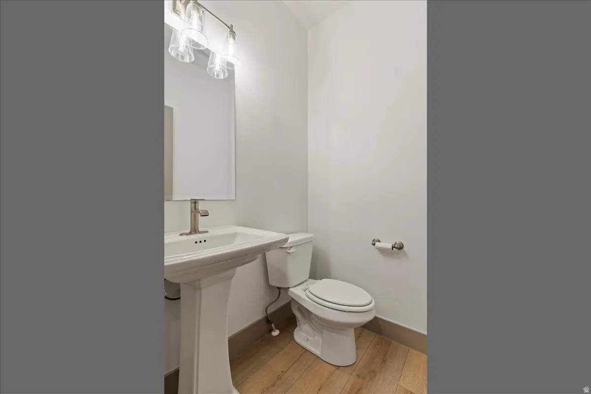 Pedestal sink with a brushed nickel faucet, framed mirror, and contemporary vanity lighting