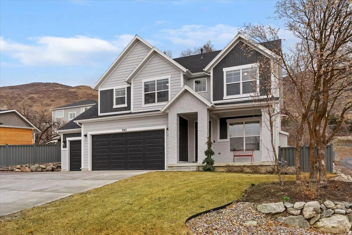 Contemporary two-story residence featuring a combination of light gray siding, dark gray board and batten accents, and white brick detailing