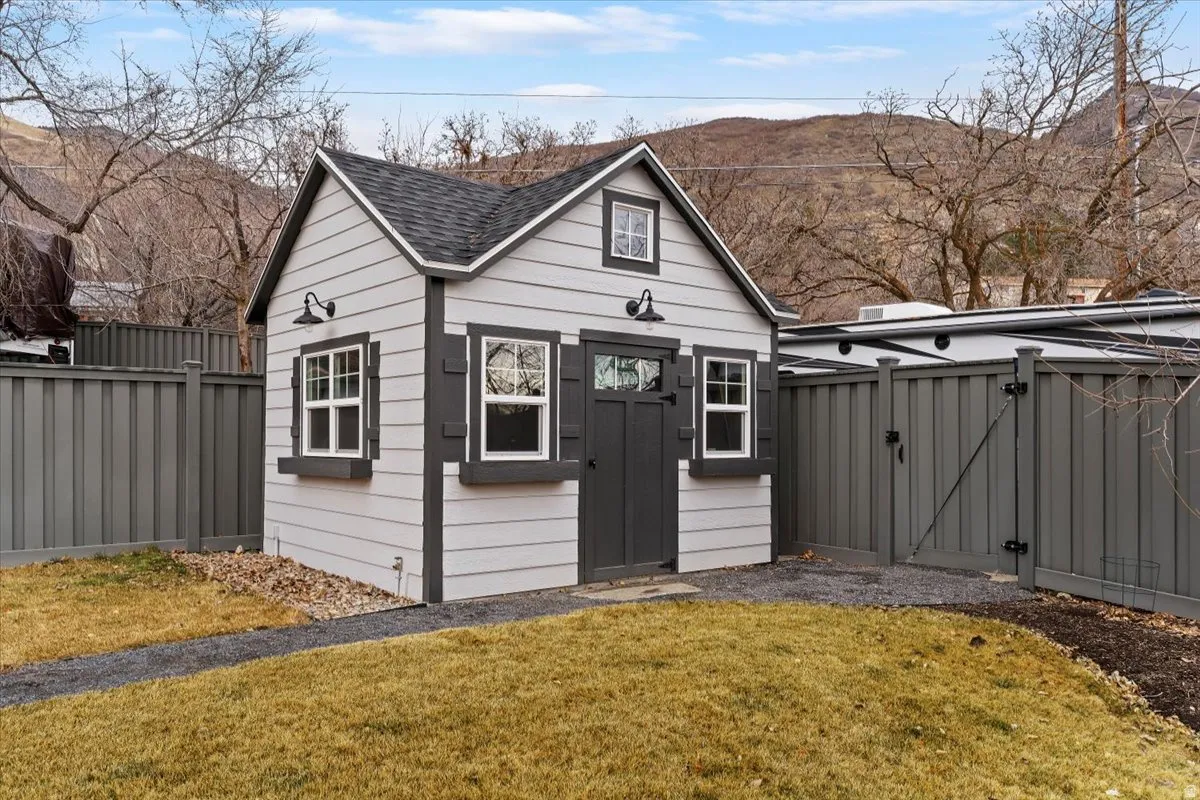 Detached outbuilding featuring horizontal siding, a gabled roof, and multiple windows
