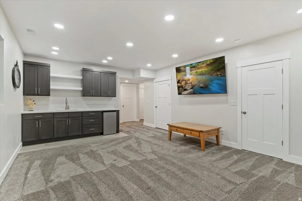 Entertainment room with a built-in wet bar, recessed lighting, and a wall-mounted television