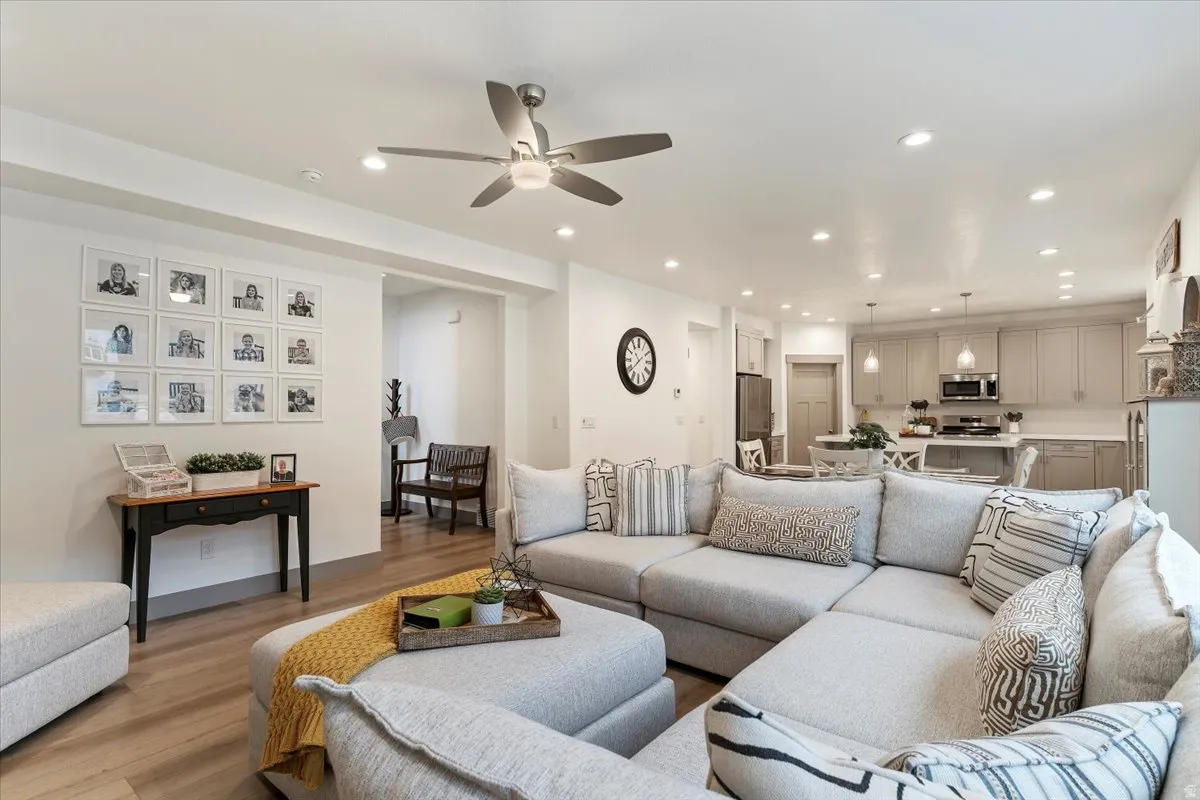Open-concept living area featuring wood-finish flooring, a ceiling fan with integrated lighting, and recessed lighting throughout