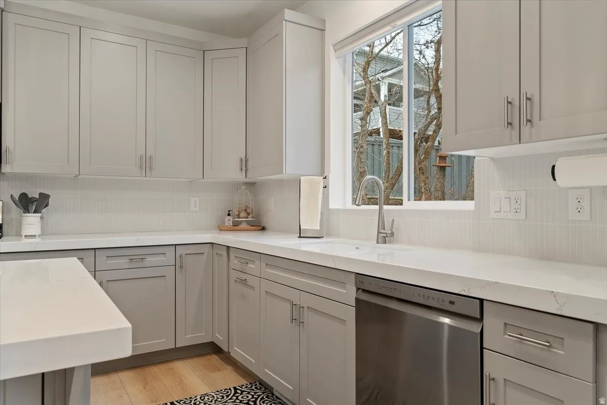 Contemporary kitchen featuring light gray cabinetry, white countertops, and a full-height tile backsplash