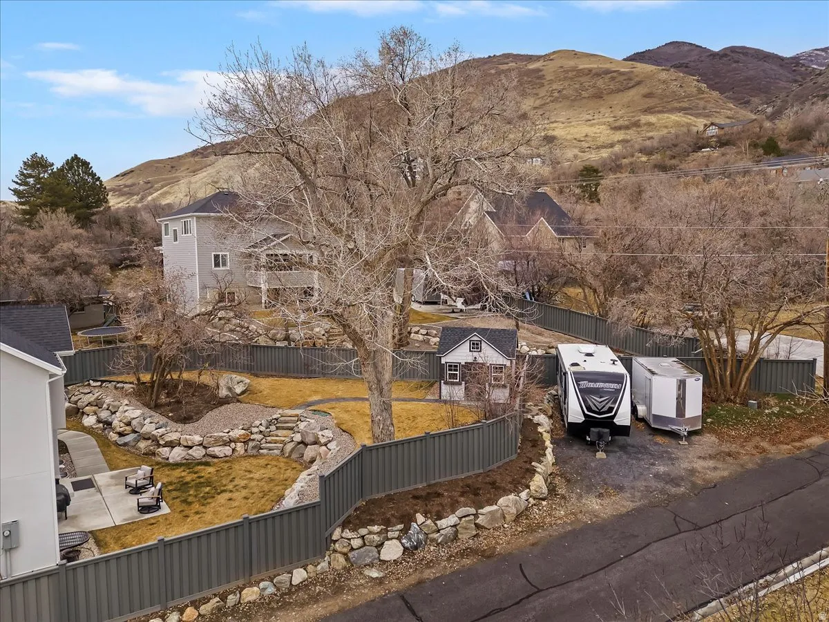 Expansive terraced yard featuring natural rock retaining walls, a mature tree, and a small outbuilding