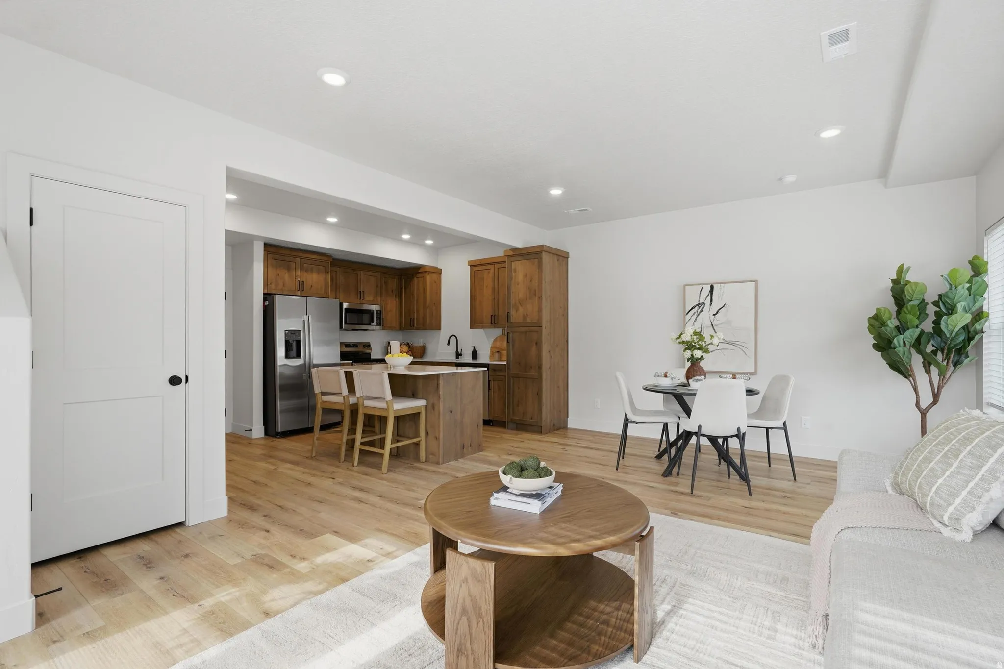 Open-concept living space featuring wood-finish flooring, recessed lighting, and white walls