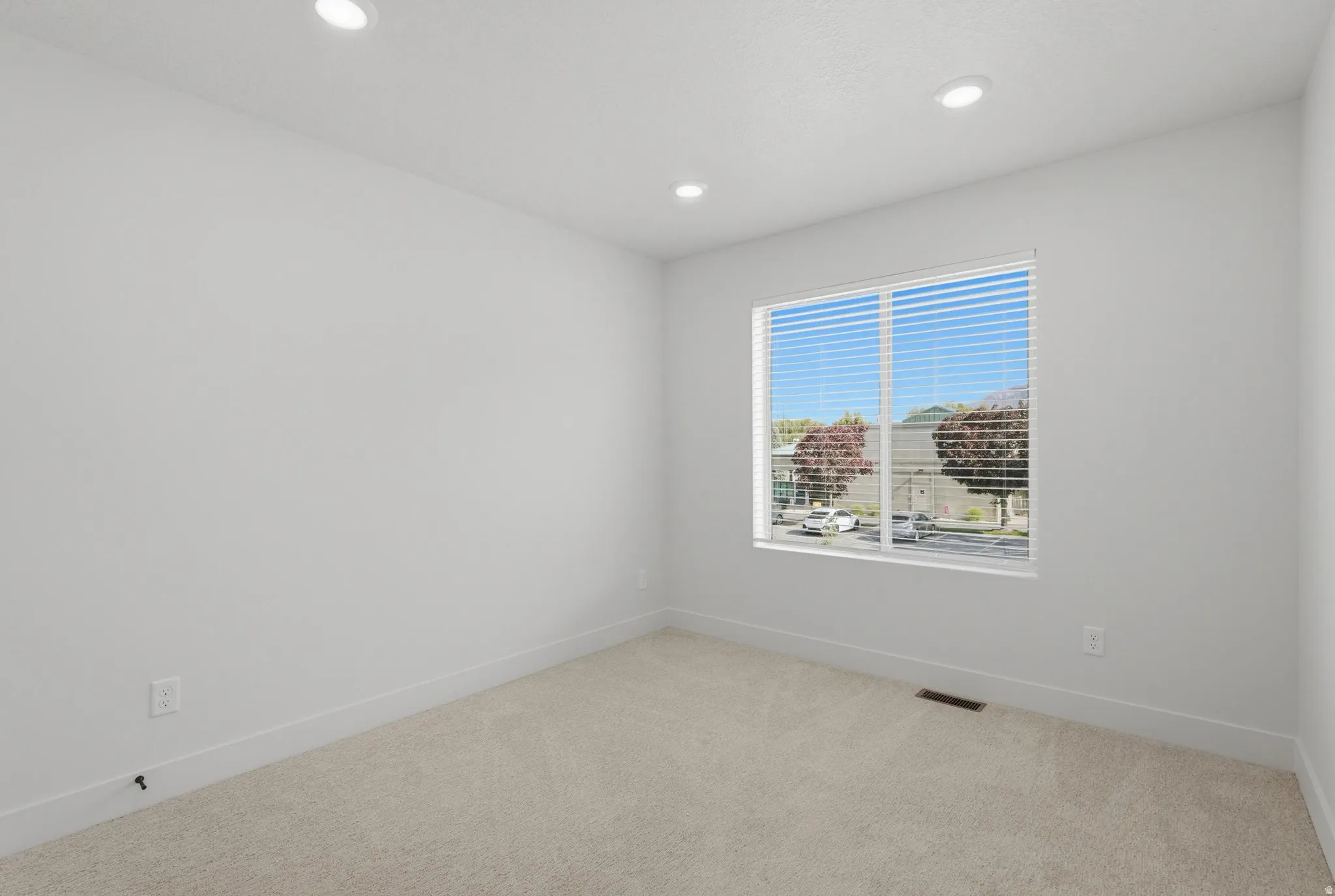 Light-filled interior space with neutral carpeting and recessed ceiling lighting