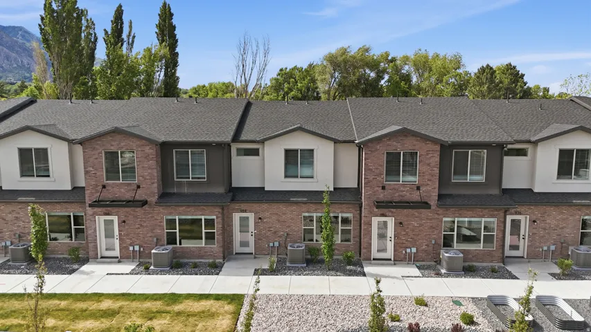Contemporary townhome row featuring brick and stucco facades, dark shingle roofing, and individual front entrances