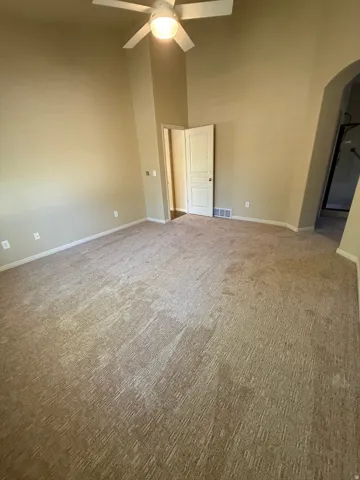 Vaulted ceiling with a ceiling fan, neutral carpeting, archway entry, and a paneled door