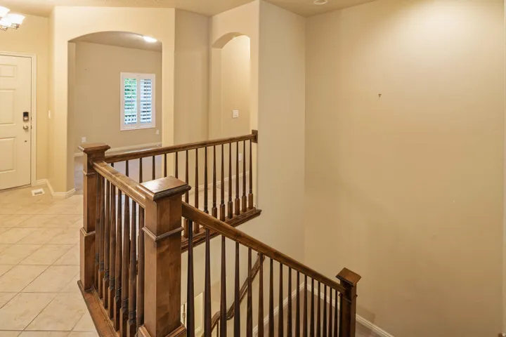 Hardwood staircase with dark balusters, arched doorways, and tile flooring in the entry