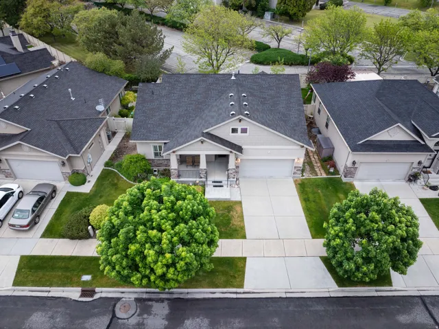 Single-family residence featuring a welcoming covered porch, attached two-car garage, and a neatly manicured front yard with mature trees