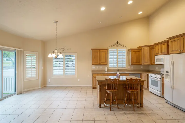Open-concept kitchen and dining area featuring vaulted ceilings, recessed lighting, and tile flooring