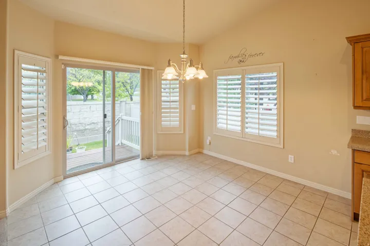 Tiled flooring dining area featuring a vaulted ceiling and a brass-finish chandelier