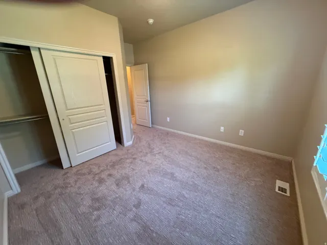 Carpeted room featuring a double-door closet with internal shelving, neutral wall tones, and trim
