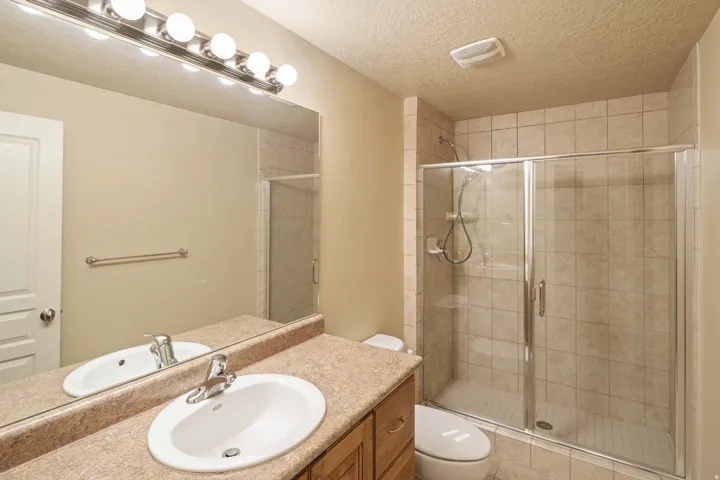 Full bathroom featuring a single vanity with an oval sink, a speckled countertop, and a chrome faucet