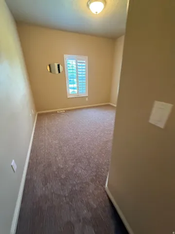 Textured brown carpet, white window shutters, and a semi-flush mount ceiling light