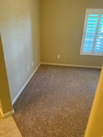 Carpeted flooring, neutral wall tones, window with white louvered shutters, white trim