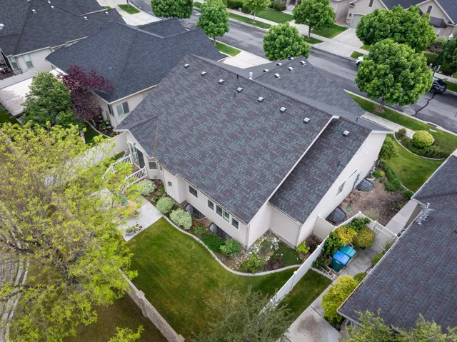 Aerial perspective showcasing a pitched shingle roof, light-colored siding, and a fenced backyard with a manicured lawn
