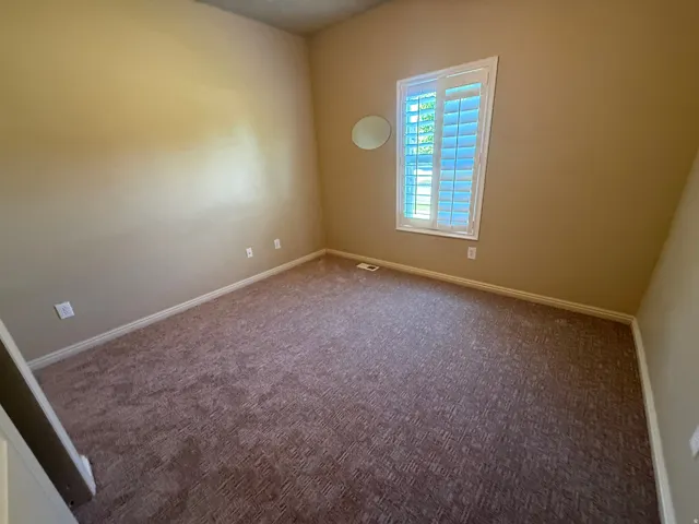 Soft pile carpeting, window with plantation shutters, neutral wall tones, and white trim work