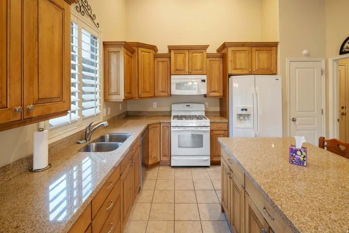 Kitchen featuring warm wood cabinetry, light speckled countertops, and a central island