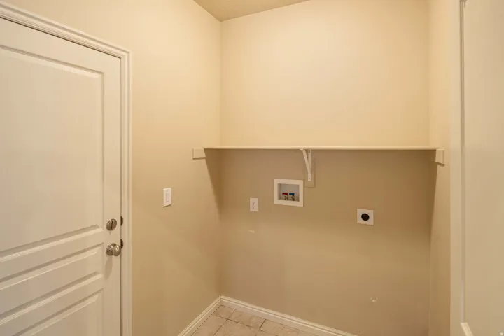 Utility room featuring a paneled door, neutral wall paint, and a built-in storage shelf