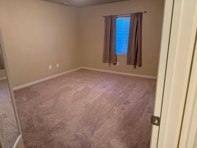 Wall-to-wall carpeting with baseboard trim, window with blinds, and neutral wall paint