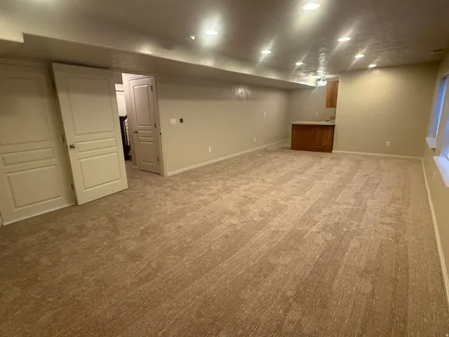 Spacious room with recessed lighting, light-toned carpeting, and light-colored walls