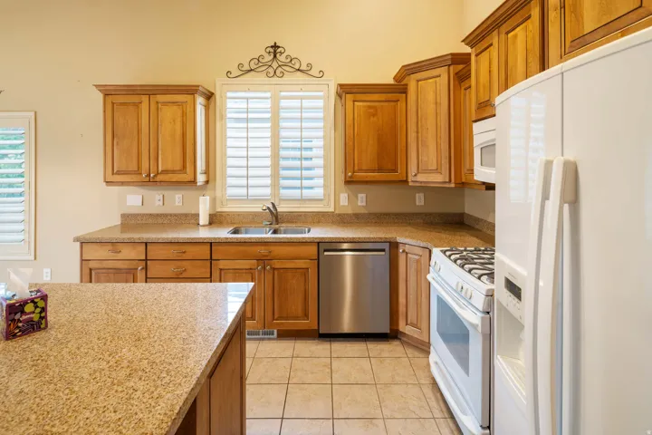 Kitchen featuring wood cabinetry, light speckled countertops, and tile flooring