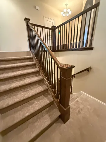 Carpeted staircase featuring a dark wood newel post and balusters