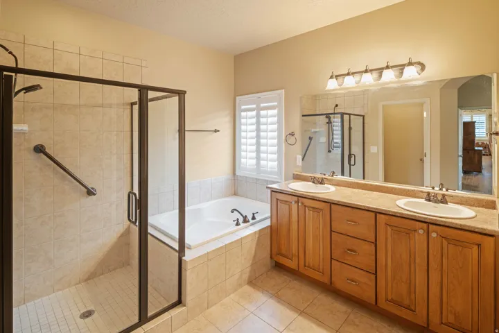 Spacious bathroom featuring a dual-sink vanity with wood cabinetry and a light-toned countertop