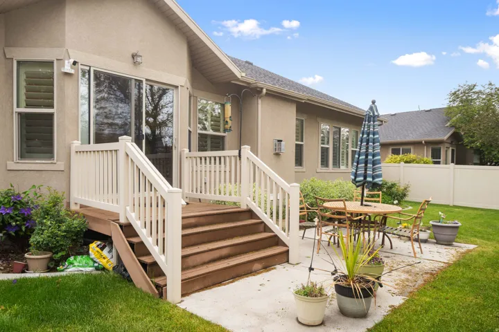 Exterior patio featuring a concrete surface, a multi-tier wood deck with white railings, and a sliding glass door entry